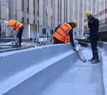 Hot applied polyurea being sprayed onto a roof surface