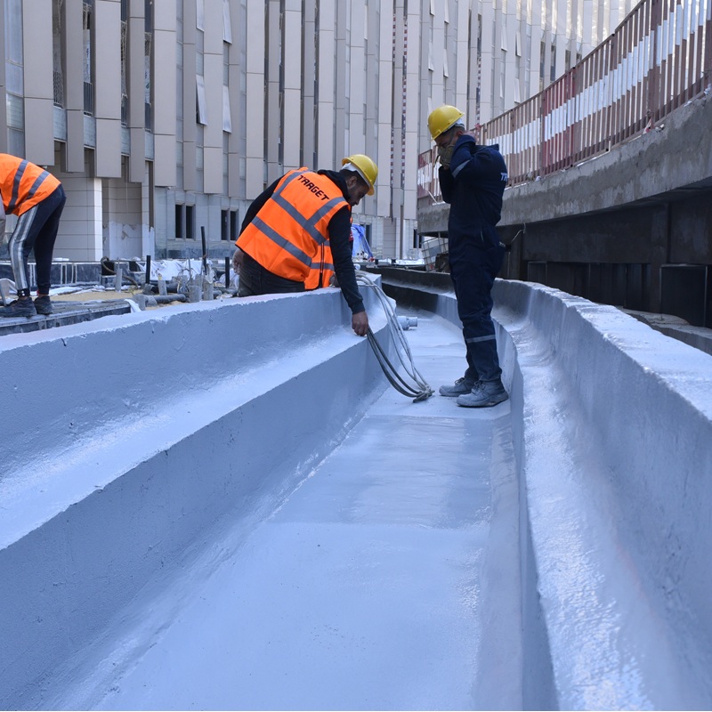Precision Polyurea Waterproofing Solutions Applied Engineers in protective gear spray-applying polyurea waterproofing membrane on a concrete surface.