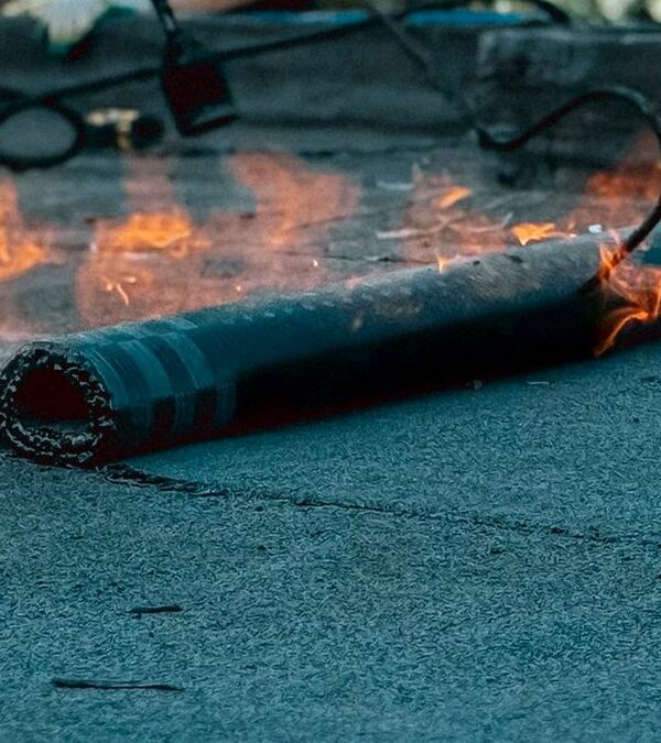 Bitumen waterproofing membranes being torch-applied as the roll is unrolled on a flat roof