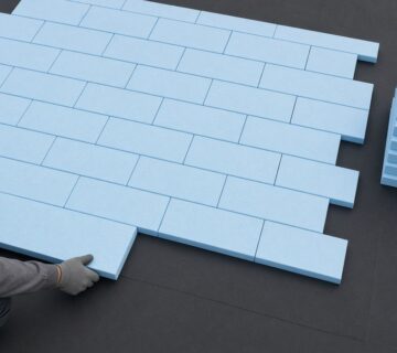Laying blue XPS insulation boards tightly over the roof waterproofing membrane