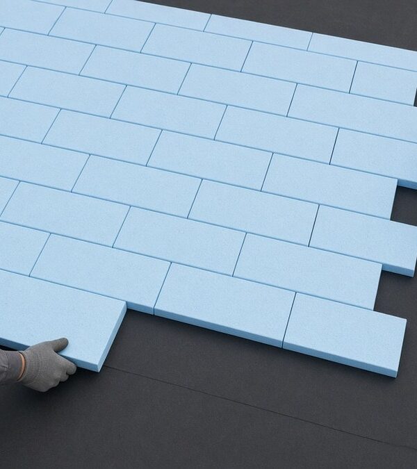 Laying blue XPS insulation boards tightly over the roof waterproofing membrane